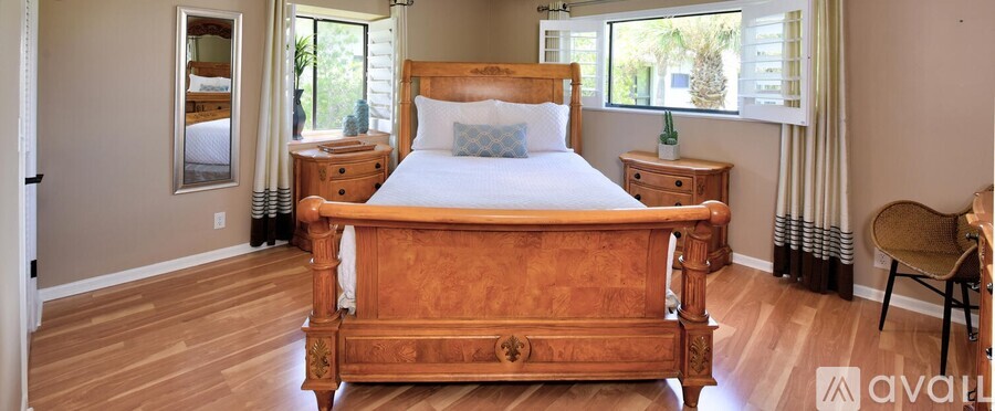 A bedroom with a large bed and a chair.