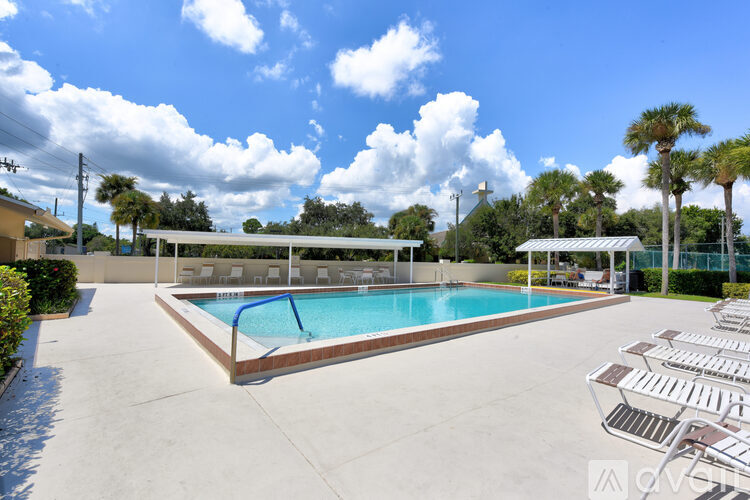 A pool surrounded by a concrete patio and a white fence.