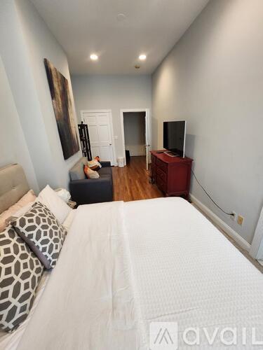 A bedroom with a large bed and a television in the corner.