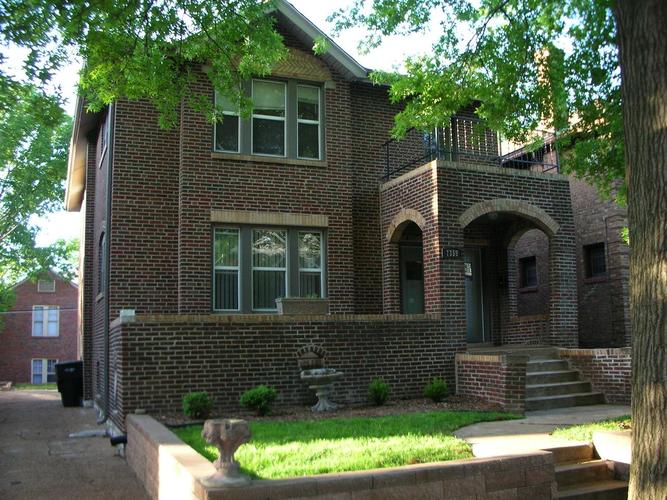 A red brick house with a green lawn in front.