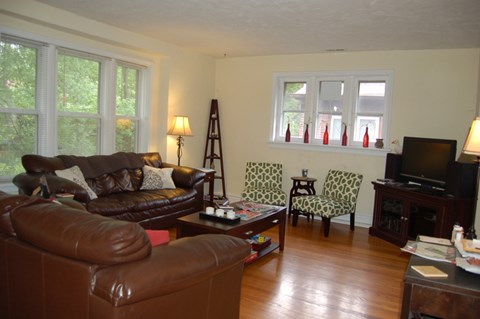 A living room with brown leather couches and a wooden floor.