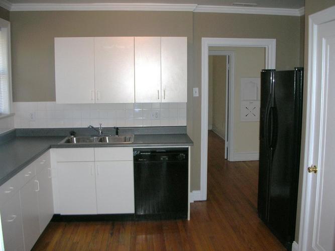 A kitchen with white cabinets and a black fridge.
