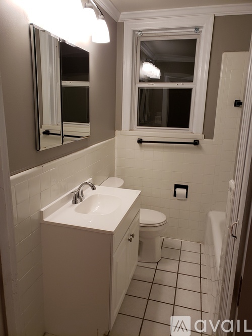 A bathroom with a sink, toilet and mirror.