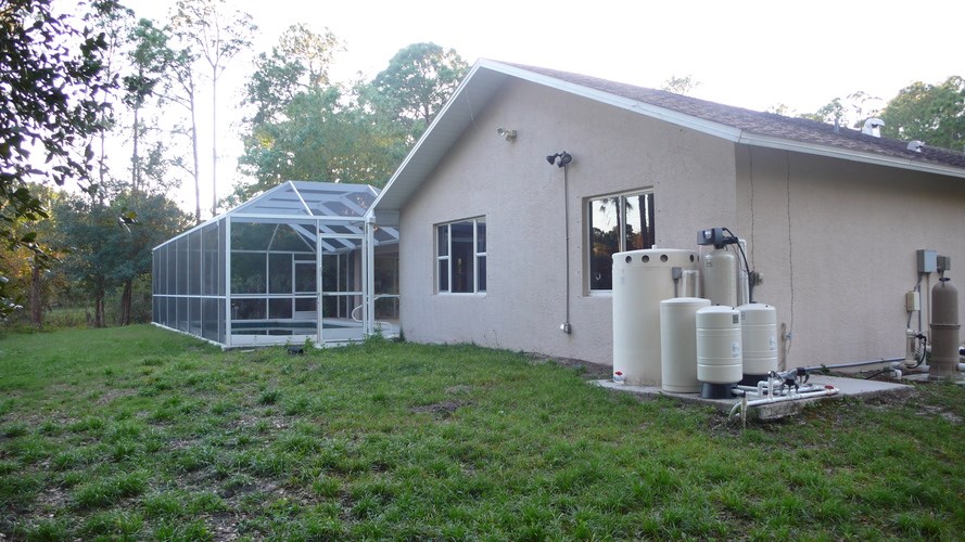 A house with a green lawn and a greenhouse attached to it.
