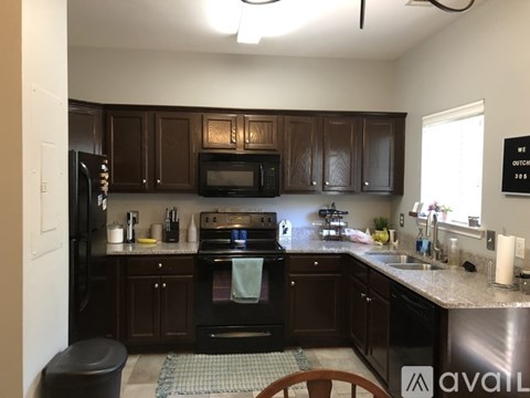 A kitchen with dark brown cabinets and black appliances.