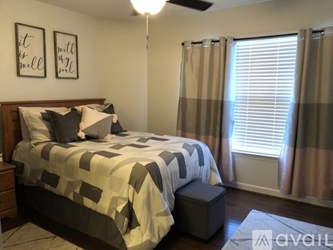 A bedroom with a bed, nightstand, and window with curtains.