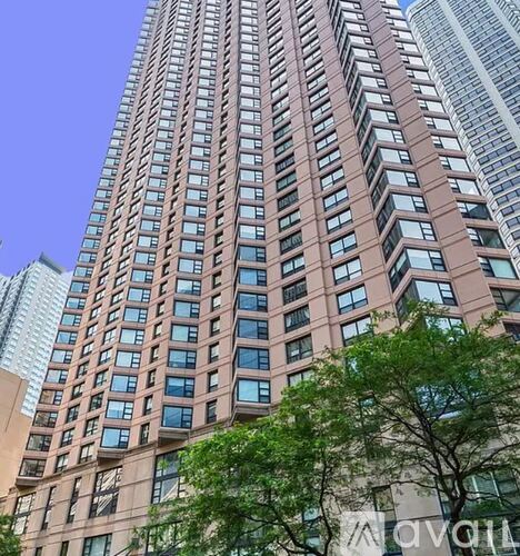 A tall building with many windows stands in front of other buildings.