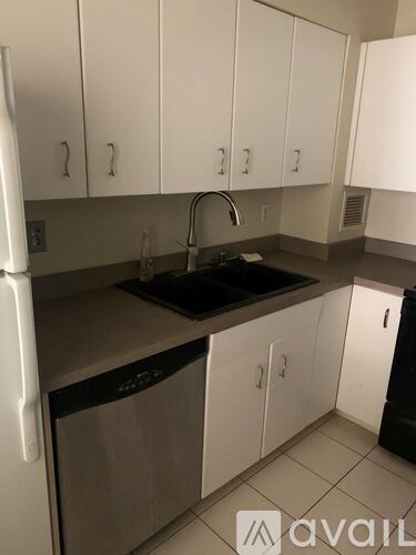 A kitchen with white cabinets and a black dishwasher.