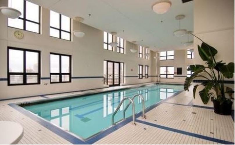 A large indoor swimming pool with a diving board.