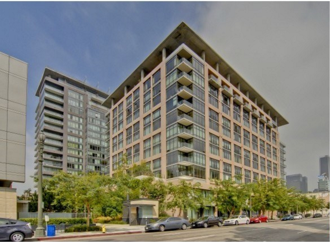 A modern multi-story building with a parking lot in front.