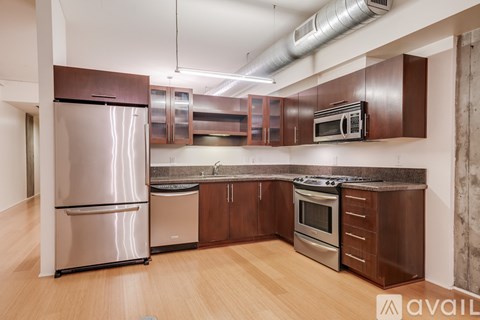 A kitchen with wooden cabinets and a stainless steel refrigerator.