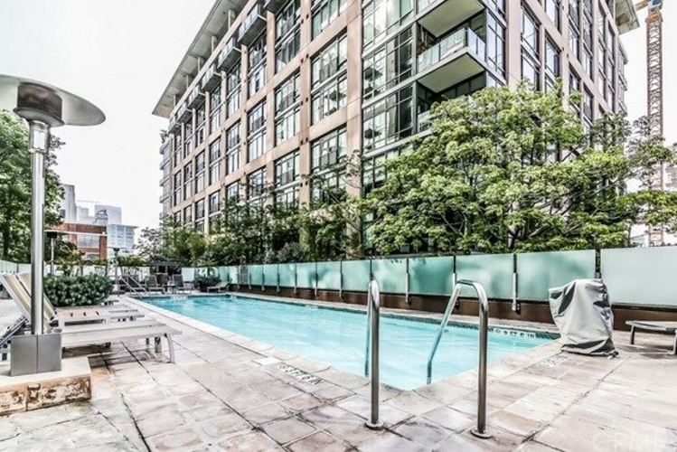 A pool surrounded by a green fence and trees.