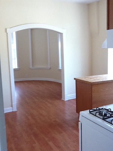 A white stove sits in a kitchen with wood floors.
