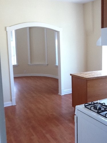 A white stove sits in a kitchen with wood floors.