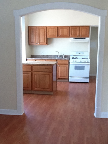 A kitchen with wooden cabinets and a white stove.