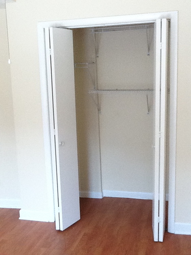 A white empty fridge in a room with wooden floors.
