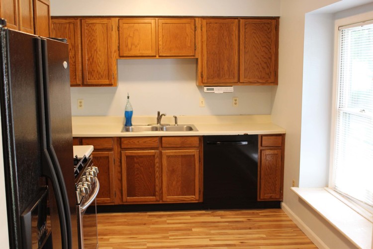 A kitchen with wooden cabinets and a black refrigerator.
