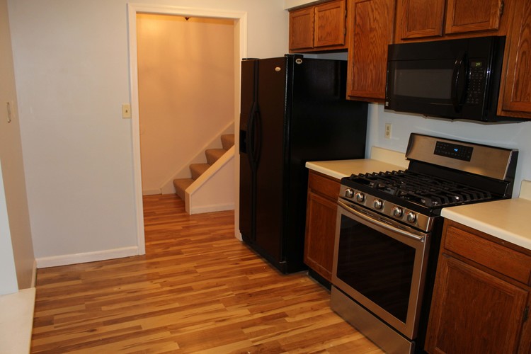 A kitchen with a black refrigerator, stove, and microwave.