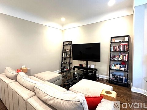 A living room with a large television and a bookshelf.