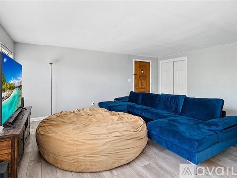 A living room with a blue couch and a round wooden ottoman.