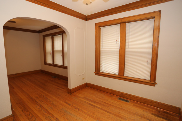 A room with wooden floors and a window with blinds.