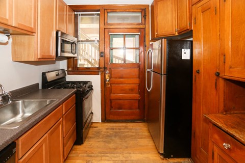 A kitchen with wooden cabinets and a black fridge.