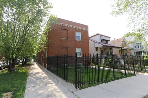 A brick building with a black fence in front of it.