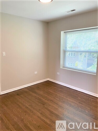 A room with wooden flooring and a window showing a view of a street.