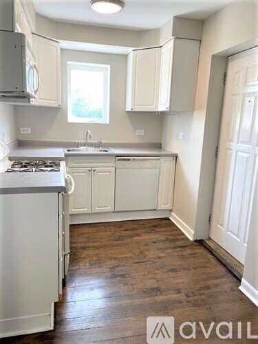 A kitchen with white cabinets and a wooden floor.