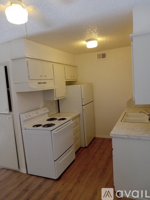 A small kitchen with white appliances and wooden floors.