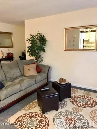 A living room with a couch, a potted plant, and a mirror.