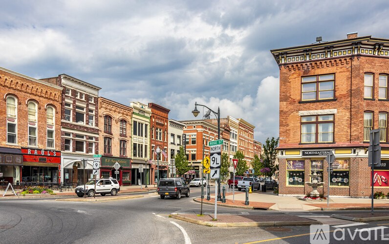 A street view of a town with buildings on either side and a car driving on the road.