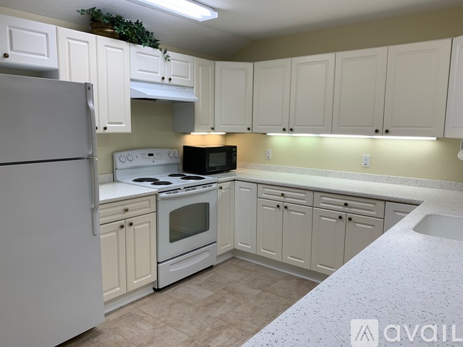 A kitchen with white appliances and cabinets.