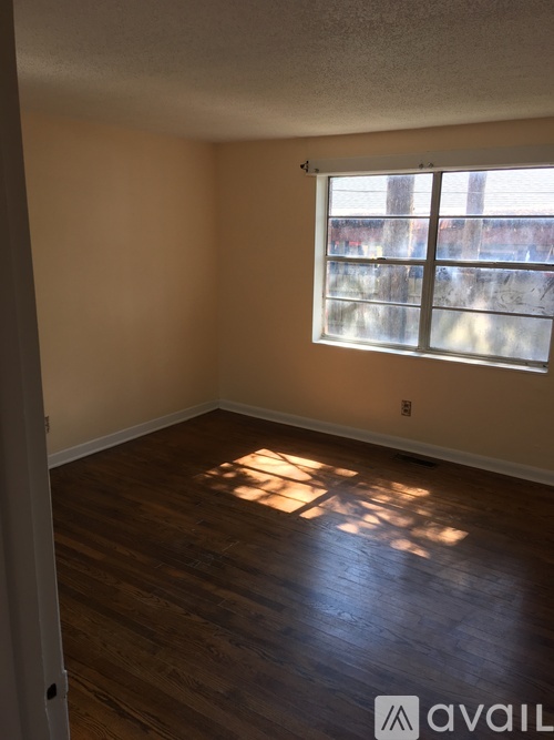 A room with wooden flooring and a window letting in sunlight.