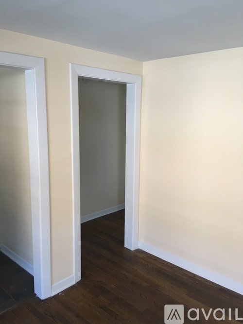 A room with a white door and a wooden floor.