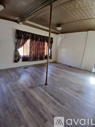 A room with wooden flooring and a window with curtains.