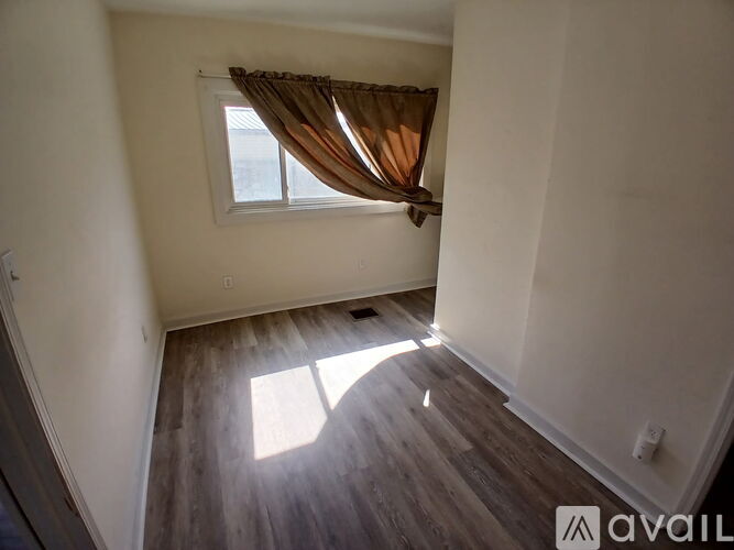 A room with a window and wooden flooring.