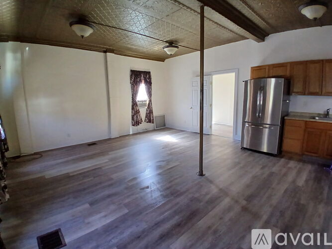 A spacious room with wooden flooring and a ceiling fan.