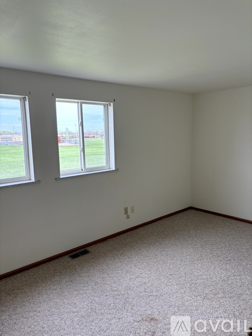 A room with two windows and carpeted floor.