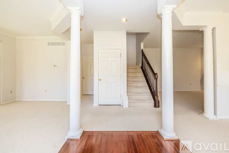 A white room with a wooden floor and a staircase.