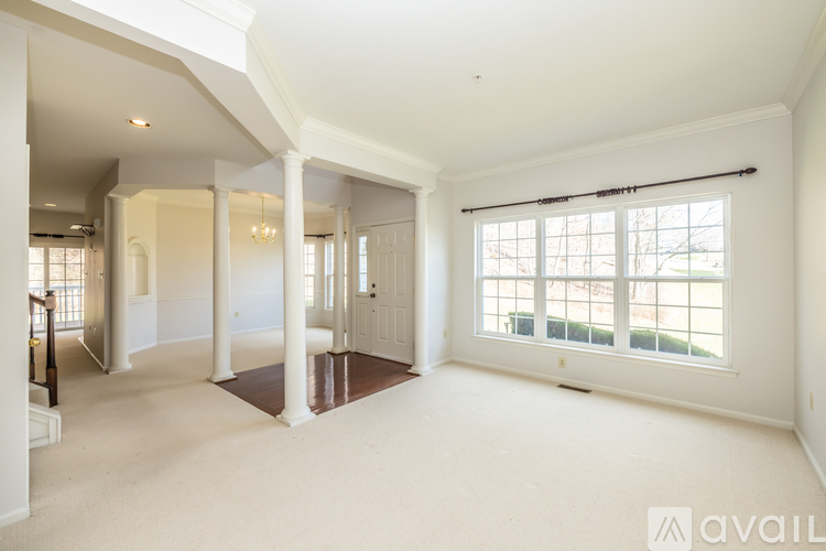 A spacious living room with a large window and a door leading to another room.