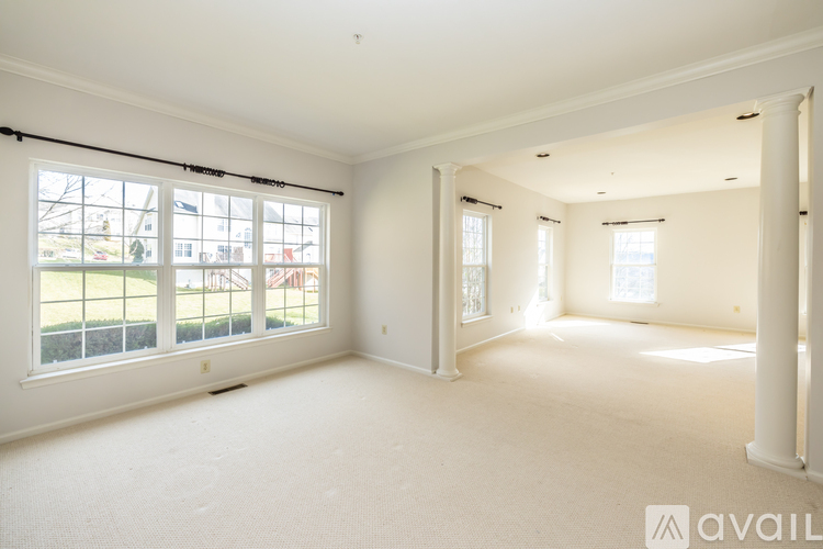 A spacious empty room with large windows and white walls.