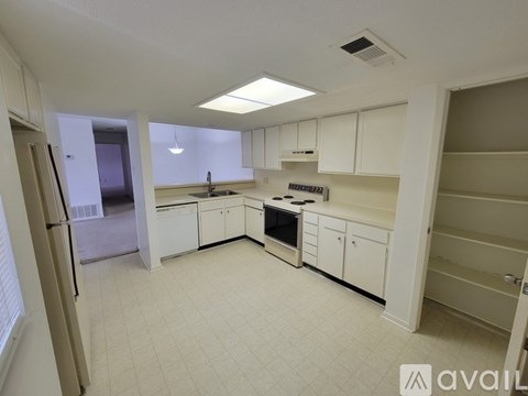 A kitchen with white cabinets and appliances is available for rent.