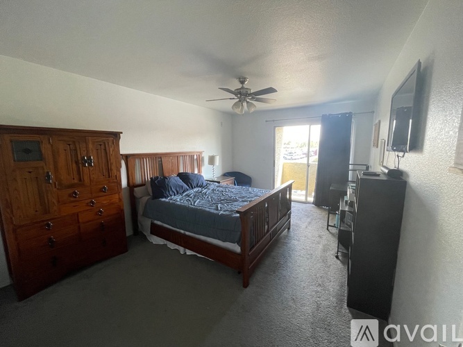 A bedroom with a bed, dresser, and ceiling fan.