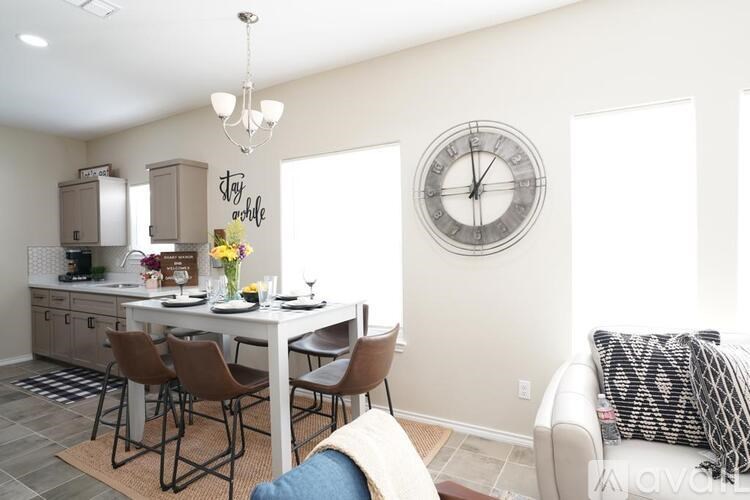 A kitchen with a table and chairs and a clock on the wall.