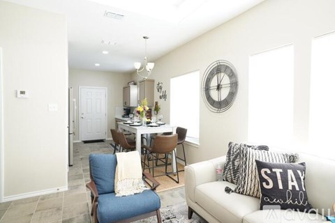 A living room with a white couch and a dining table with chairs.