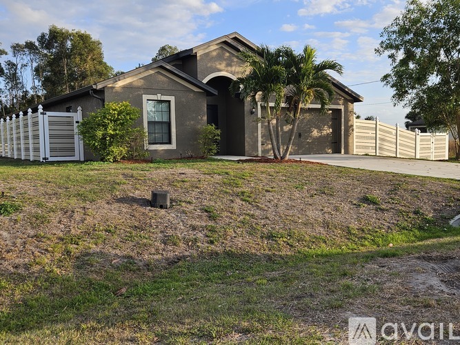 A house with a white fence and a palm tree in front.