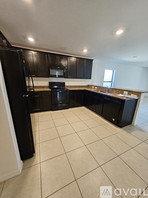 A kitchen with black cabinets and appliances.
