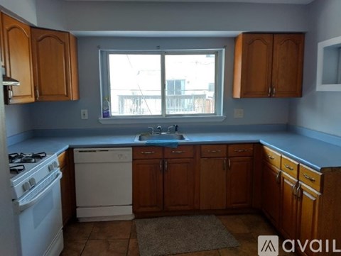 A kitchen with wooden cabinets and a white stove top oven.