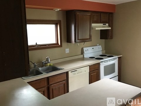 A kitchen with a white stove top oven and a white dishwasher.